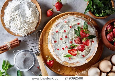 Strawberry Tart Covered With Whipped Sour Cream Surrounded By Organic Ingredients Over White Backgro