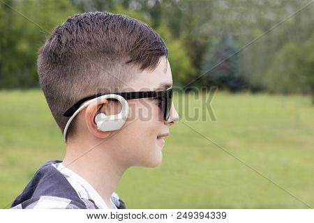 Close Up Side Portrait Of Stylish Boy With Earphones Posing Outdoors. Happy Child In Trendy Sunglass