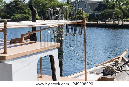 A Clam Boat Backed In To Its Dock With Three Claming Tings On Top Looking Over The Blue Water If The