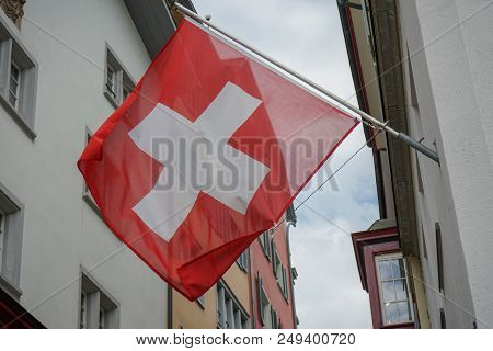 Swiss Flag Hanging From Building Facade In Old Town
