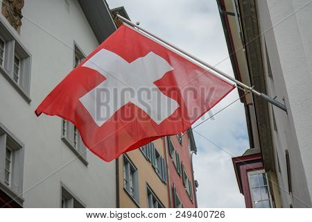 Swiss Flag Hanging From Building Facade In Old Town