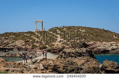 Naxos, Greece - July 23, 2016: View of the Portara doorway, on top of the Palatia hill. Portara is the ruins of an unfinished glorious ancient Greek temple.