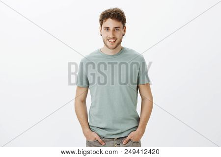 Portrait Of Charming Flirty Aduly Guy With Blond Hair, Holding Hands On Pants And Smiling Broadly, T