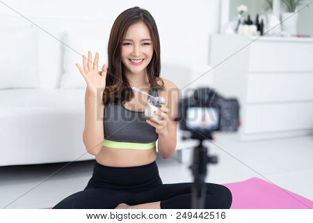 Pretty Healthy Young Asian Woman Blogger Holding With Glass Of Natural Yogurt And Saying Hi With Rec