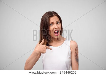You Mean Me? A Picture Of A Puzzled Confused Young Beautiful Woman Dressed In A White Top Looking At
