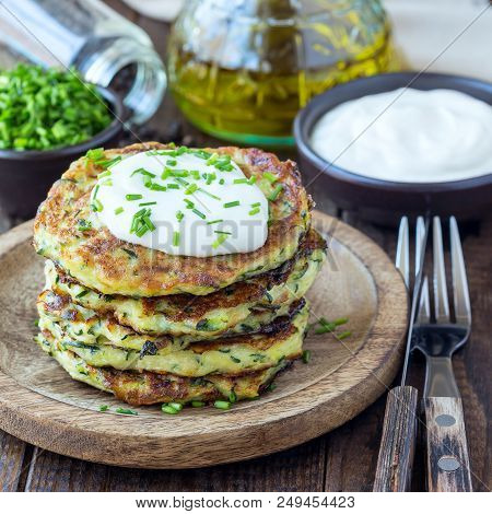 Vegetarian Zucchini Fritters Or Pancakes, Served With Greek Yogurt And Green Onion On A Wooden Backg