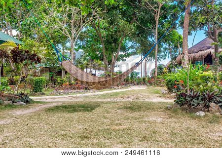 Tropical Beach. A Hammock Between Two Palm Trees On The Beach. Concept Of Rest. Beautiful Beach.