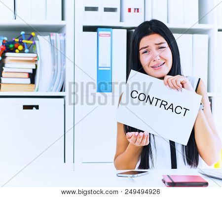 Young Unhappy Female Office Worker Ripping Contract At The Desk.