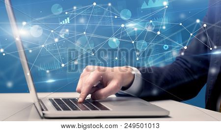 Businessman typing on laptop with linked reports charts grapghs around