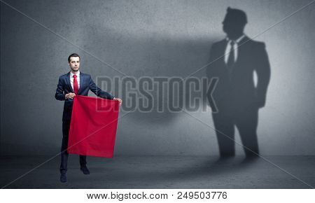 Businessman standing with red cloth on his hand and his shadow on the background