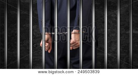 Close convicted man with handcuffs behind grids