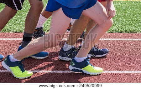 High School Boys Are Set To Start A Long Iinterval Race On A Red Track During Outdooe Track And Fiel