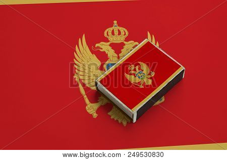Montenegro Flag  Is Pictured On A Matchbox That Lies On A Large Flag.