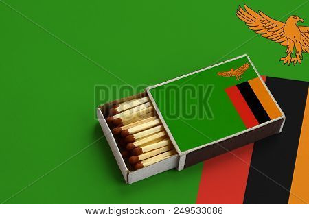Zambia Flag  Is Shown In An Open Matchbox, Which Is Filled With Matches And Lies On A Large Flag.