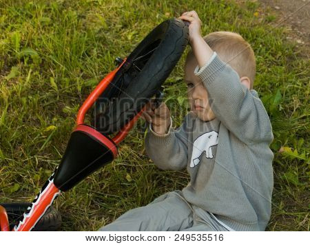 A Little Boy Dreams Of Becoming A Mechanic. The Guy Trains On A Bicycle. The Child Spins The Nuts On