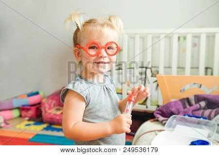 Close Up Portrait Of Smiling Cute Blondy Toddler Baby Girl Playing Doctor With Plastic Toy Glasses A