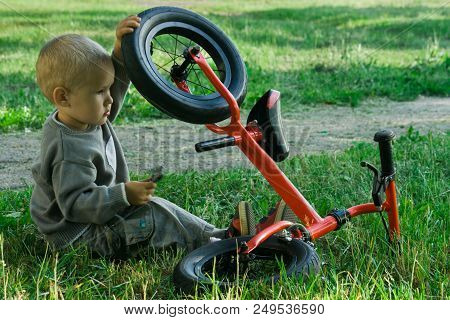 A Little Boy Dreams Of Becoming A Mechanic. The Guy Trains On A Bicycle. The Child Spins The Nuts On
