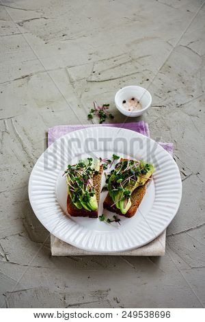 Balanced Vegan Breakfast Or Lunch Close Up. Tasty Avocado Toasts On Plate With Micro Greens Over Lig