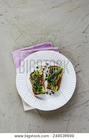 Plate Of Healthy Avocado Toasts With Micro Greens Over Light Concrete Background. Balanced Vegan Bre