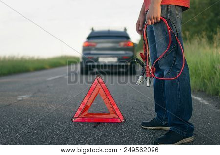 Low Car Battery Charge. Need Recharging. Driver Holding A Automobile Cable Starter In The Hands.