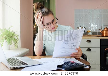 Indoor Shot Of Young European Caucasian Girl Looking At Financial Documents At Home With Deeply Bore