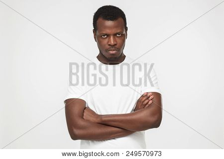 Indoor Picture Of Young Handsome African American Man Pictured Against Gray Background Wearing White