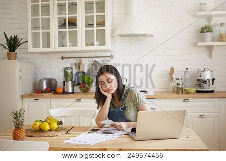 Frustrated Upset Young Dark Haired Female Feeling Unhappy, Reading Notification From Bank, Sitting A