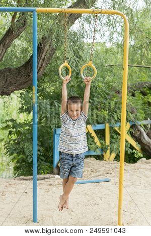 A Little Boy Is Doing Phisical Exercises On A Sportsground.