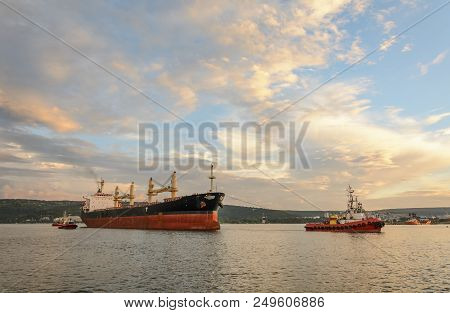 Tug Boat Entering The Harbor With Big Cargo Boat.
