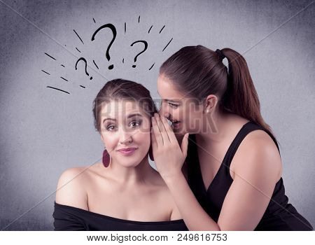 A teenager girl looking confused with drawn question marks above the head, while a girlfriend whispers something in her ear concept.