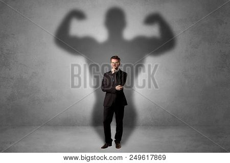 Lovely serious businessman standing with a muscular powerful shadow behind his back