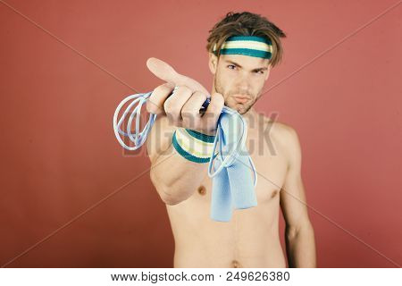 Man With Naked Torso Holds Jump Rope On Pink Background, Close Up. Athlete With Confident Face Getti