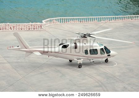 White Helicopter Lands On A Helipad Near The Sea
