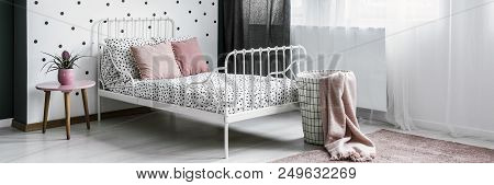 Bright Teenage Girl Bedroom Interior With Dotted Sheets And Pink Pillows On Metal Bed, Green Plant O