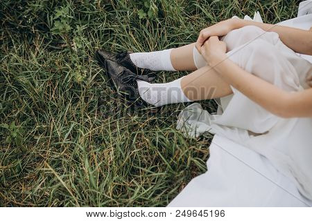 Woman Peasant Sitting On Grass In White Dress And Black Shoes