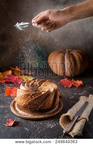 Bundt Cake With Saffron And Rum Covered With White Glaze On Rustic Background With Autumn Decoration