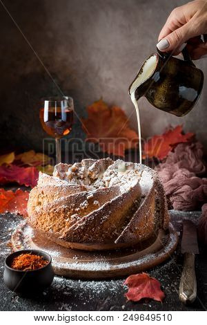 Bundt Cake With Saffron And Rum Covered With White Glaze On Rustic Background With Autumn Decoration