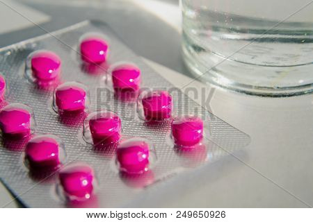 Pink Pills With Glass Of Water Isolated On White Background