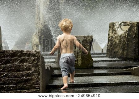 Cute Toddler Playing In The City Fountain. Back View.
