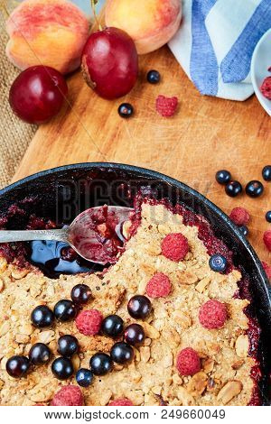 Food Background. Crumble With Blueberries In The Black Cast-iron Frying Pan On The Wooden Cutting Bo