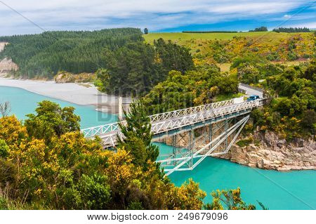 Bridge over river Rakaia with a view at  turquoise river and blooming yellow gorse