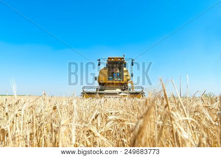Harvester In The Foreground On Rustic Background Working In The Field