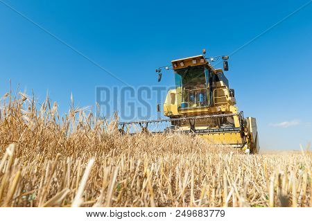 Harvester In The Foreground On Rustic Background Working In The Field