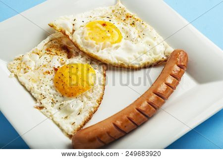 Traditional Clasic Breakfast Fried Eggs And Sausage On A White Square Porcelain Plate.