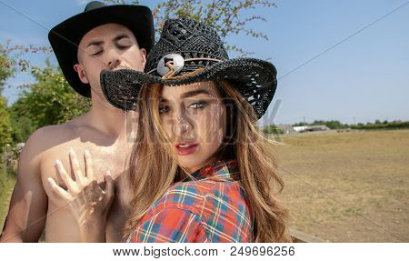 Cowboy And Cowgirl Couple Arguing. She Faces Away From Him As He Tries To Grab Her