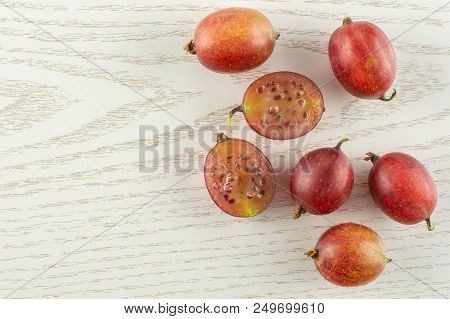 Group Of Five Whole Two Halves Of Fresh Red Gooseberry Hinnomaki Variety Flatlay On Grey Wood