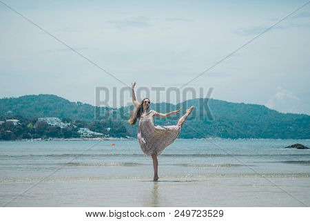 Beautiful Girl Dancing On The Beach. Portrait Of A Woman In White Clothes On The Sea. Dancer On The 