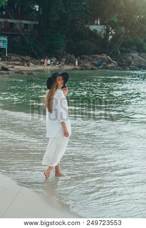 Handsome Girl In Hat On The Beach Background. Portrait Of A Woman In White Clothes And Balck Hat On 