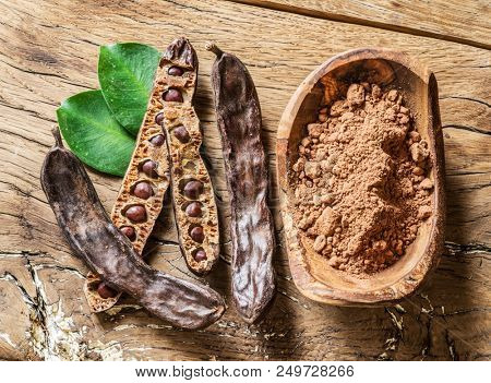Carob pods and carob beans on the wooden table.