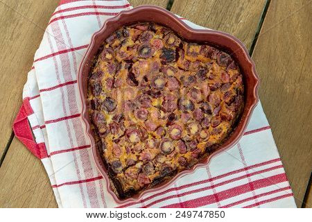 A Clafouti With Cherries In The Form Of Heart On A Wooden Table